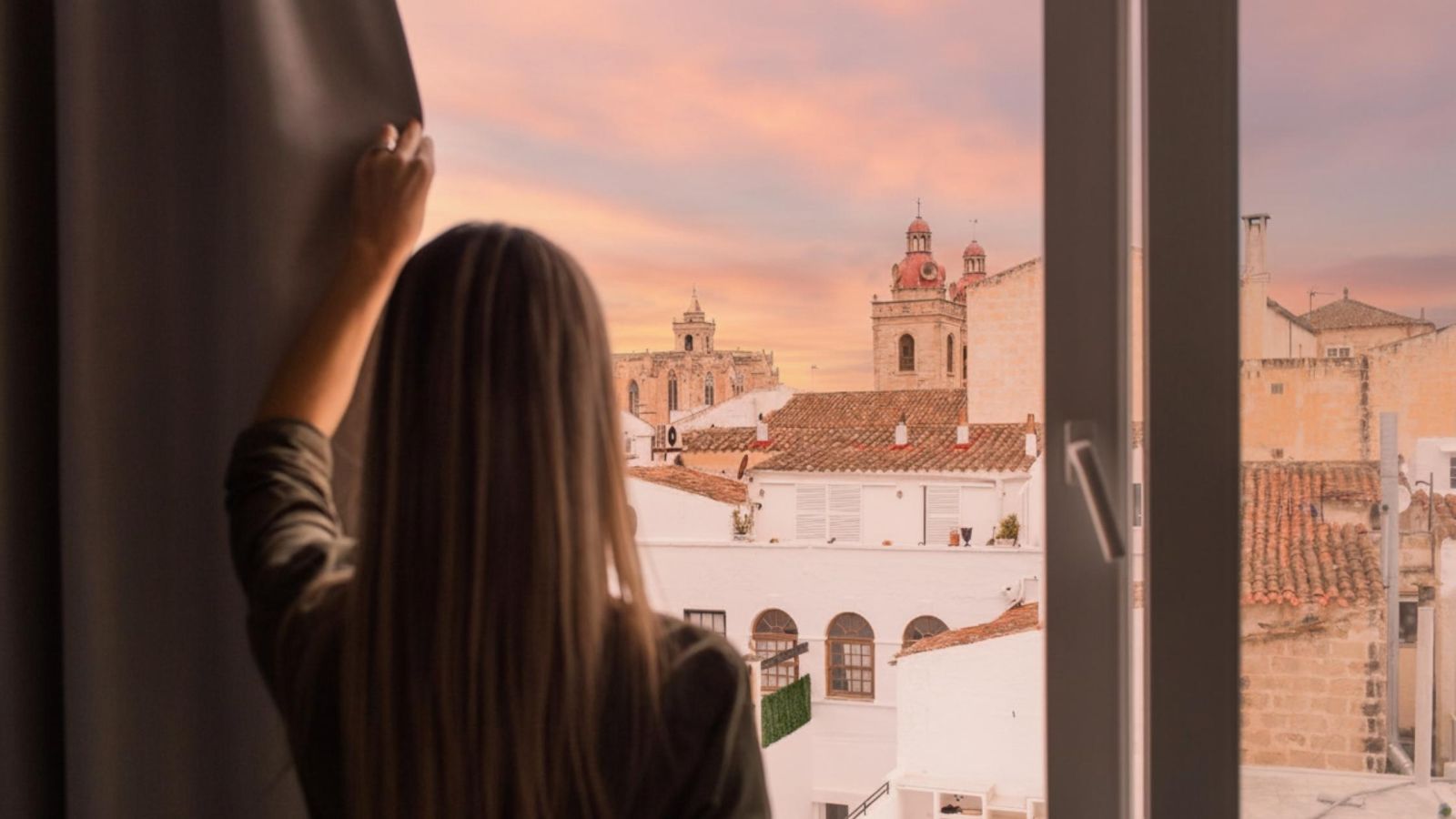 Person looking out of a window towards Ciutadella’s historic centre