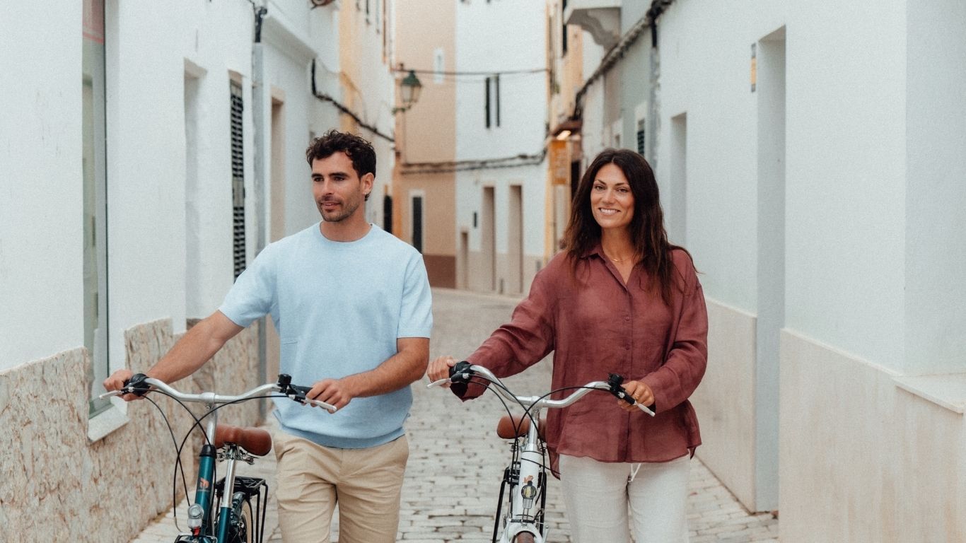 Two people with bicycles in a street in Ciutadella’s old town