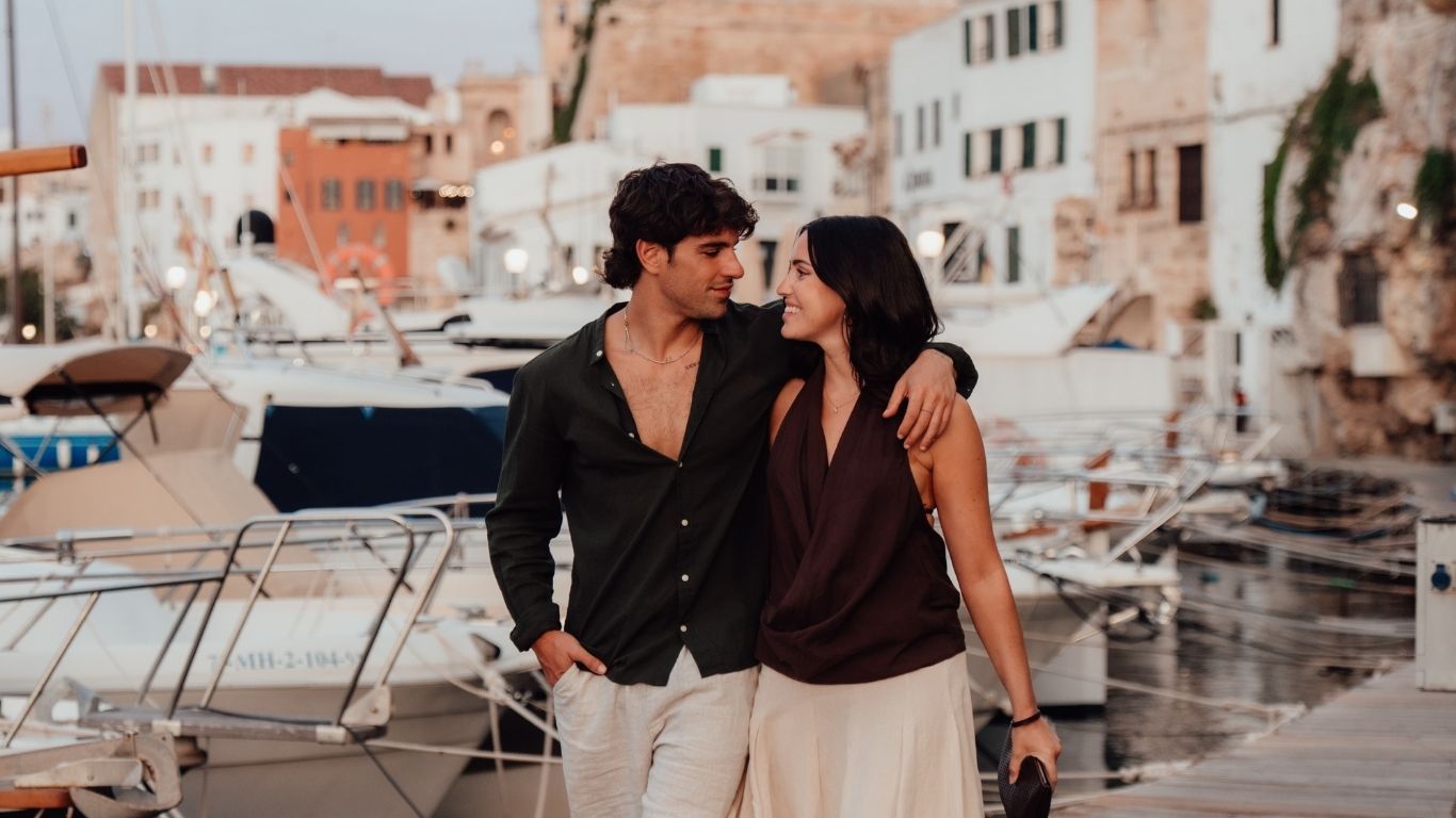 A couple beside the moored boats in Ciutadella harbour