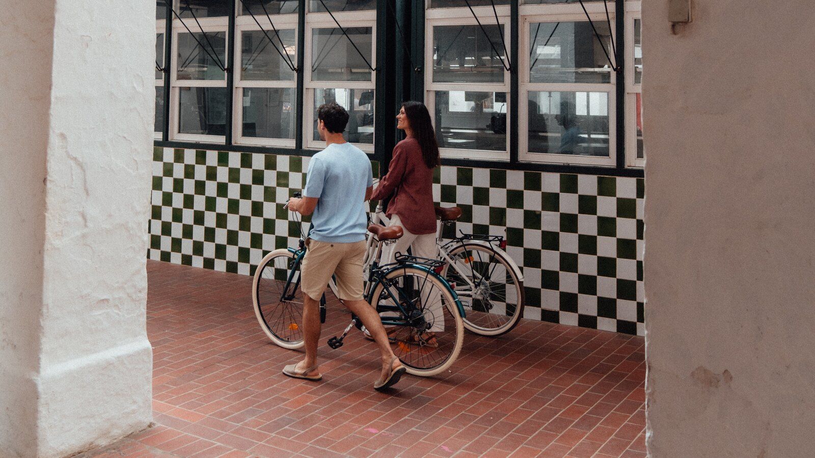 Two people with bicycles beside Ciutadella’s Mercat des Peix